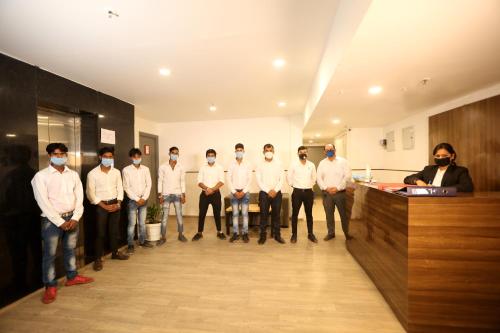 a group of men standing in a hallway wearing masks at Hotel Grand Arcasia in Ghaziabad