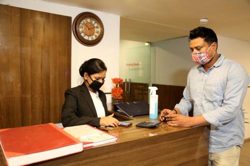 a man and a woman standing at a reception desk at Hotel Grand Arcasia in Ghaziabad