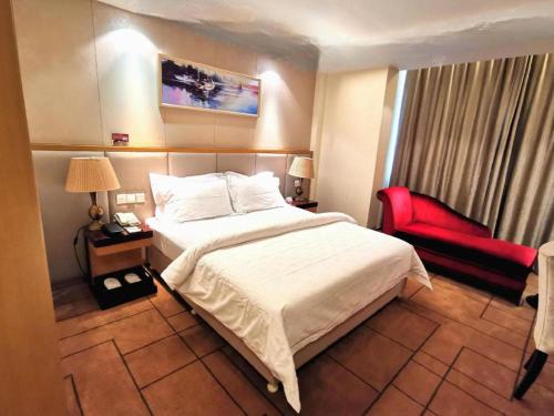 a hotel room with a bed and a red chair at Jinjiang Metropolo Shanghai Minhang in Shanghai