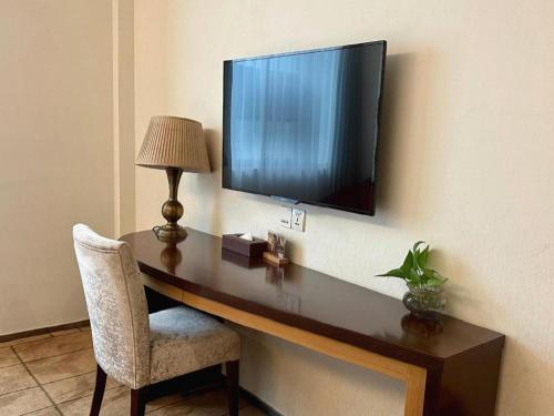 a desk with a television on a wall with a chair at Jinjiang Metropolo Shanghai Minhang in Shanghai