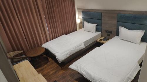 a hotel room with two beds and a table at The LEGACY HOTEL JAMSHEDPUR in Jamshedpur