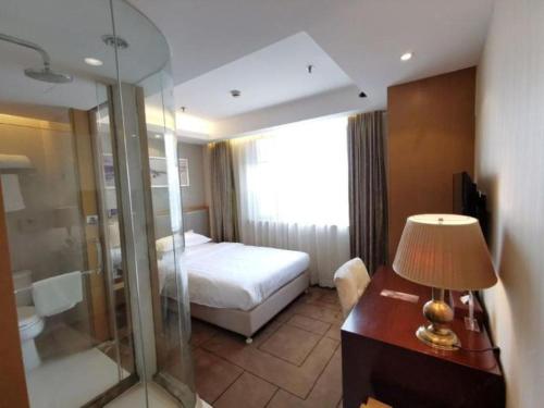 a hotel room with a bed and a desk with a lamp at Jinjiang Metropolo Shanghai Minhang in Shanghai