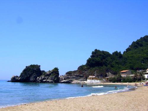 a beach with people swimming in the water at Akis Apartments Kontogialos-Pelekas in Pelekas