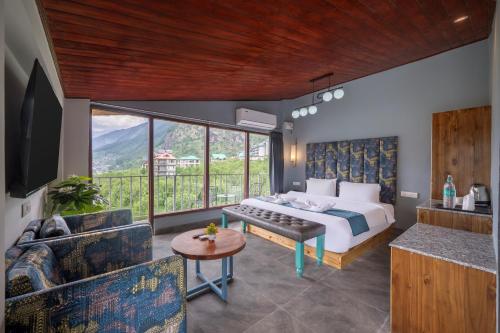 a bedroom with a bed and a couch and a table at Echor Himalayan Aurum Manali, Heating & Cooling in Manāli