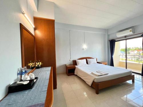 a bedroom with a bed and a table in it at Ritzy House Hotel in Chumphon