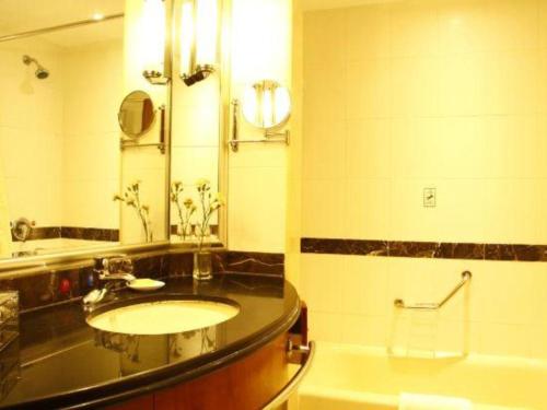 a bathroom with a sink and a mirror and a tub at Jianguo Garden Hotel in Beijing