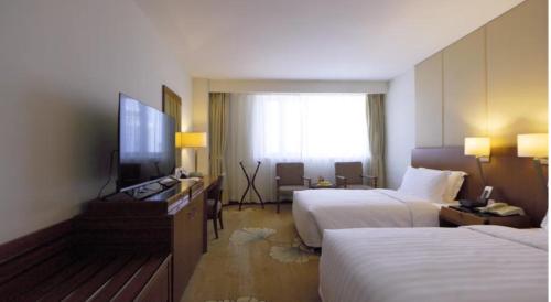 a hotel room with two beds and a flat screen tv at Jianguo Garden Hotel in Beijing