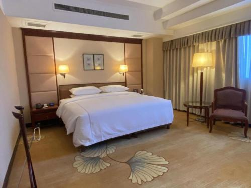 a bedroom with a large white bed and a chair at Jianguo Garden Hotel in Beijing