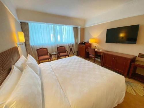 a hotel room with a large white bed and a desk at Jianguo Garden Hotel in Beijing
