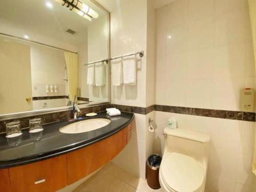 a bathroom with a sink and a toilet and a mirror at Jianguo Garden Hotel in Beijing