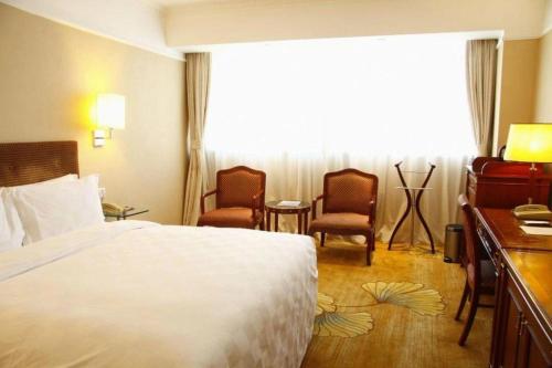 a hotel room with a bed and two chairs at Jianguo Garden Hotel in Beijing
