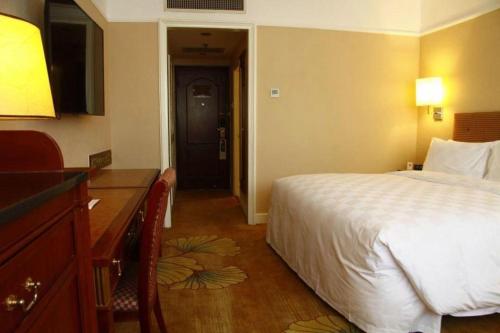 a hotel room with a bed and a dresser and a desk at Jianguo Garden Hotel in Beijing