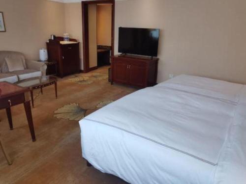 a bedroom with a bed and a tv and a couch at Jianguo Garden Hotel in Beijing