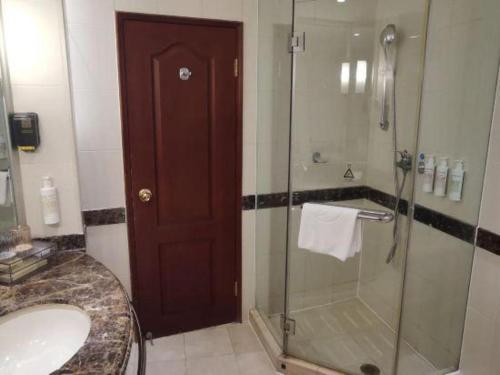 a bathroom with a glass shower and a sink at Jianguo Garden Hotel in Beijing
