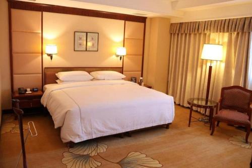 a hotel room with a large bed and a chair at Jianguo Garden Hotel in Beijing