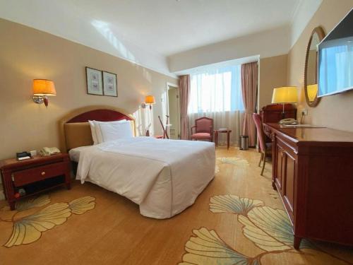 a hotel room with a large bed and a desk at Jianguo Garden Hotel in Beijing