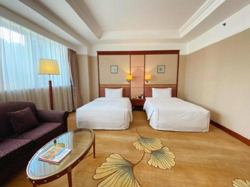 a hotel room with two beds and a couch at Jianguo Garden Hotel in Beijing