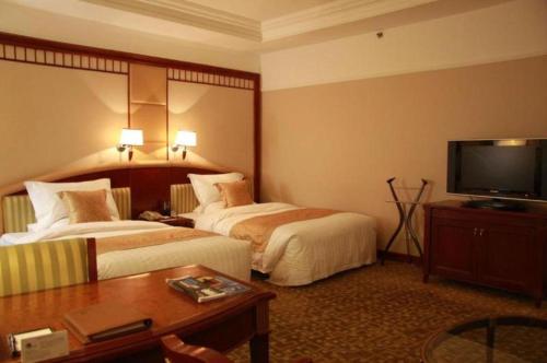 a hotel room with two beds and a flat screen tv at Jianguo Garden Hotel in Beijing