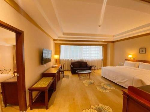 a large hotel room with a bed and a chair at Jianguo Garden Hotel in Beijing