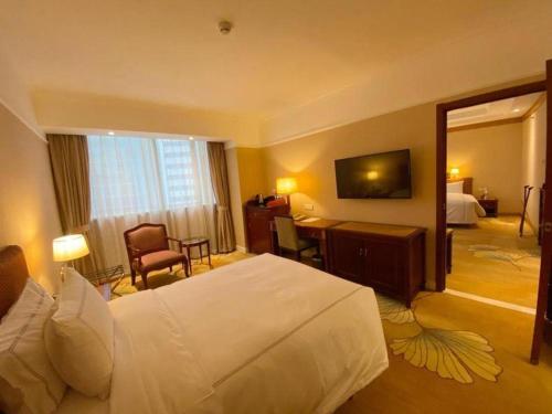 a hotel room with a large bed and a desk at Jianguo Garden Hotel in Beijing