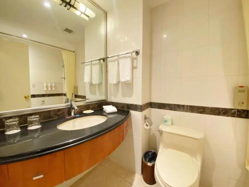 a bathroom with a sink and a toilet and a mirror at Jianguo Garden Hotel in Beijing
