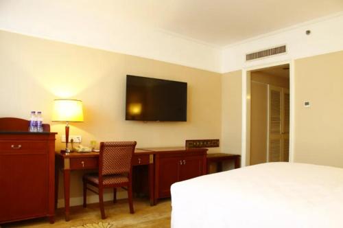a hotel room with a bed and a desk and a television at Jianguo Garden Hotel in Beijing