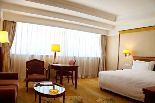 a hotel room with a bed and a desk and a table at Jianguo Garden Hotel in Beijing