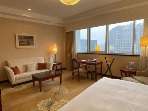 a hotel room with a bed and a couch and a desk at Jianguo Garden Hotel in Beijing