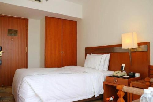 a bedroom with a white bed and a telephone at Jianguo Garden Hotel in Beijing
