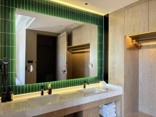 a green bathroom with two sinks and a mirror at Tianrun International Hotel in Dunhuang