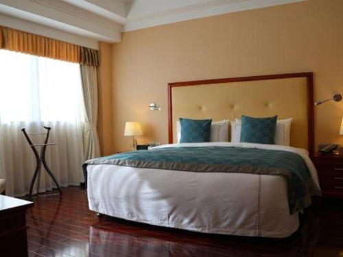 a bedroom with a large bed with blue pillows at Jianguo Garden Hotel in Beijing
