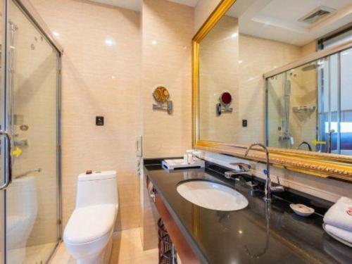 a bathroom with a toilet and a sink and a mirror at Tianrun International Hotel in Dunhuang