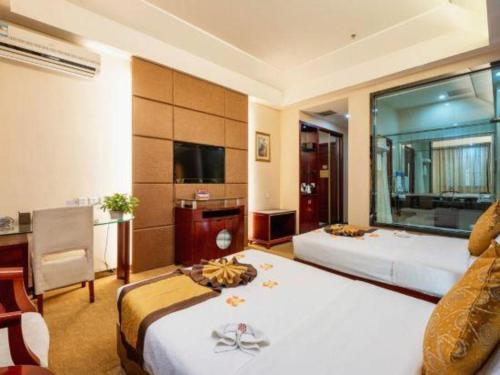 a hotel room with two beds and a desk at Tianrun International Hotel in Dunhuang