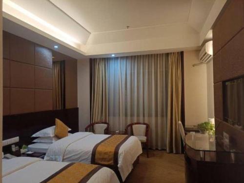 a hotel room with two beds and a table at Tianrun International Hotel in Dunhuang