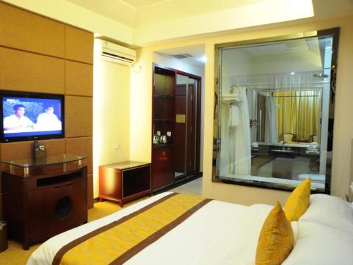 a bedroom with a bed and a tv and a bathroom at Tianrun International Hotel in Dunhuang