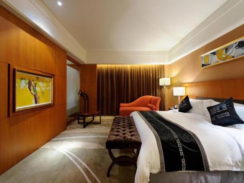 a hotel room with a large bed and a chair at Putian Depo Hotel in Putian