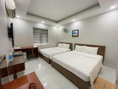 a hotel room with two beds and a desk at Duong Chau Hotel in Bùi Tiếng