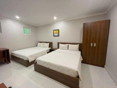 a bedroom with two beds and a wooden cabinet at Duong Chau Hotel in Bùi Tiếng