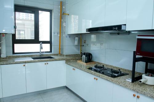 a white kitchen with a sink and a stove at Ivy Residence in Jiaozhou