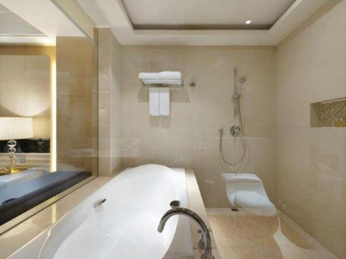 a bathroom with a tub and a toilet and a sink at Putian Depo Hotel in Putian