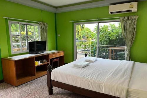a green bedroom with a bed and a flat screen tv at Hihotel Saraburi in Sara Buri