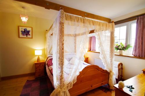 sypialnia z łóżkiem z baldachimem i białymi zasłonami w obiekcie The Old Wagon House w mieście Saint Clether