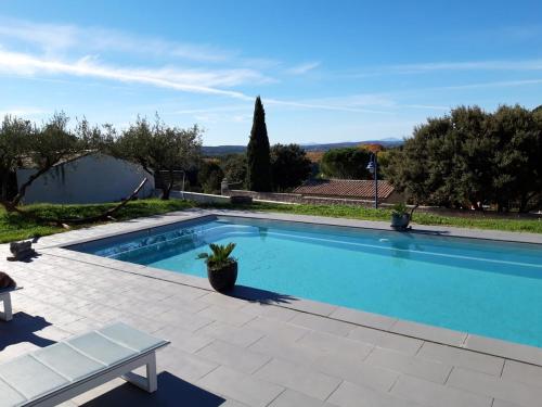une grande piscine bleue avec un banc à côté dans l'établissement La Villa des Oliviers, à Saint-Hippolyte-de-Montaigu