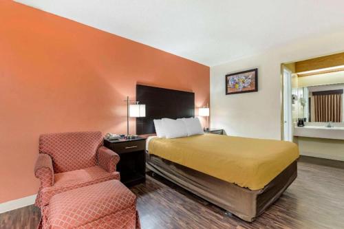 a hotel room with a bed and a chair at Econo Lodge Urbandale - Northwest Des Moines in Urbandale