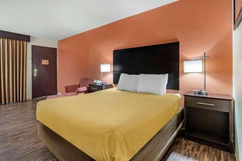 a hotel room with a bed with a yellow bedspread at Econo Lodge Urbandale - Northwest Des Moines in Urbandale