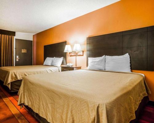 two beds in a hotel room with orange walls at Econo Lodge Urbandale - Northwest Des Moines in Urbandale