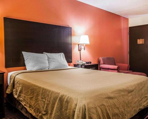 a hotel room with a large bed and two chairs at Econo Lodge Urbandale - Northwest Des Moines in Urbandale