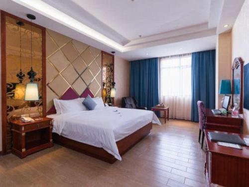 a hotel room with a large bed and a desk at Shenzhen Kai Long International Hotel in Shenzhen