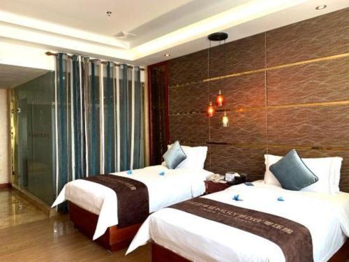 a bedroom with two beds and a wall at Shenzhen Kai Long International Hotel in Shenzhen