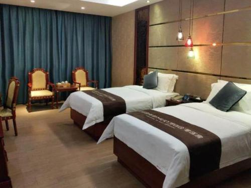 a hotel room with two beds and a table and chairs at Shenzhen Kai Long International Hotel in Shenzhen